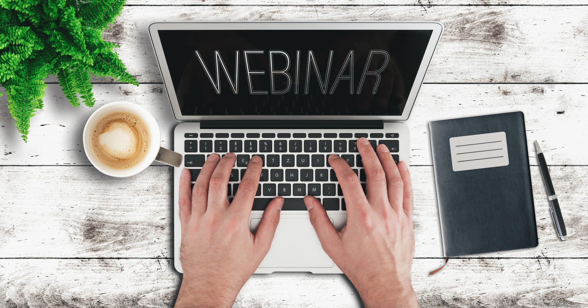 person using laptop computer on wooden table to participate in webinar