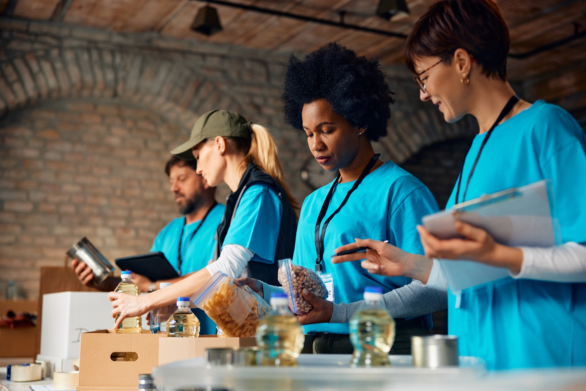 Multiracial group of volunteers packing donated food at humanitarian aid center.